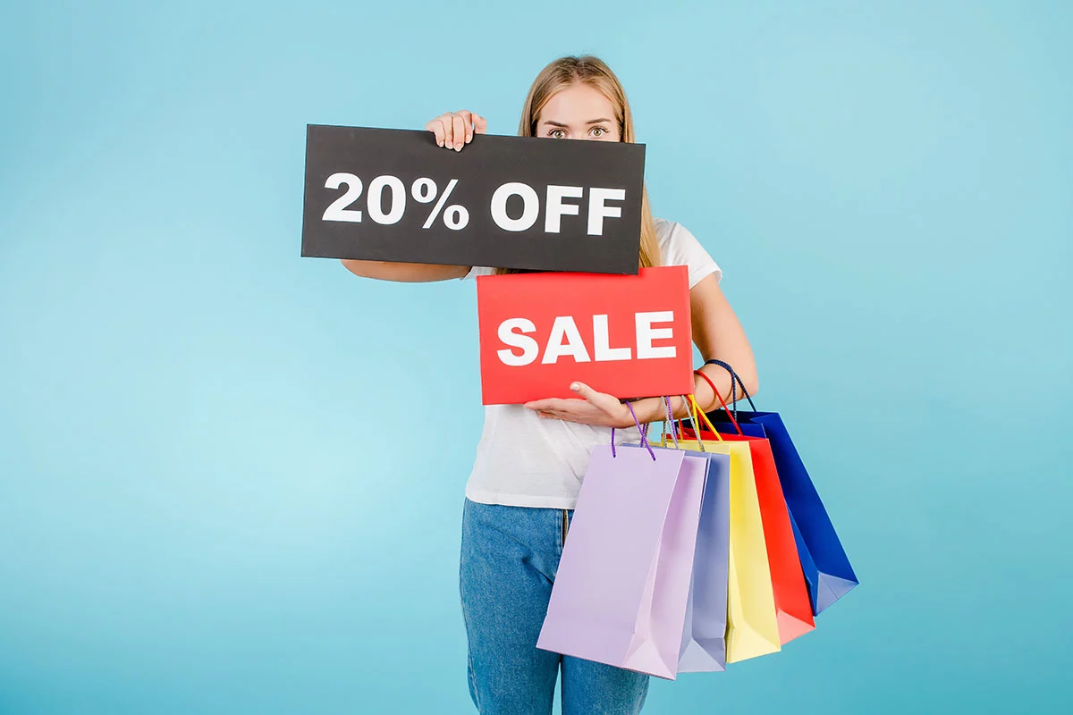 Young women holding colorful shopping bags and 20% off sale sign